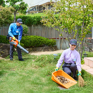 お庭の草や落ち葉を集めて清掃するスタッフ