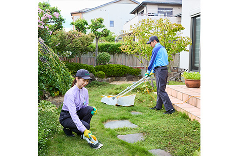 草刈りと手作業を組み合わせてお庭を整えるスタッフ
